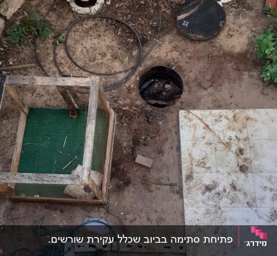 חצר עם מכסה ביוב פתוח וצינור ירוק